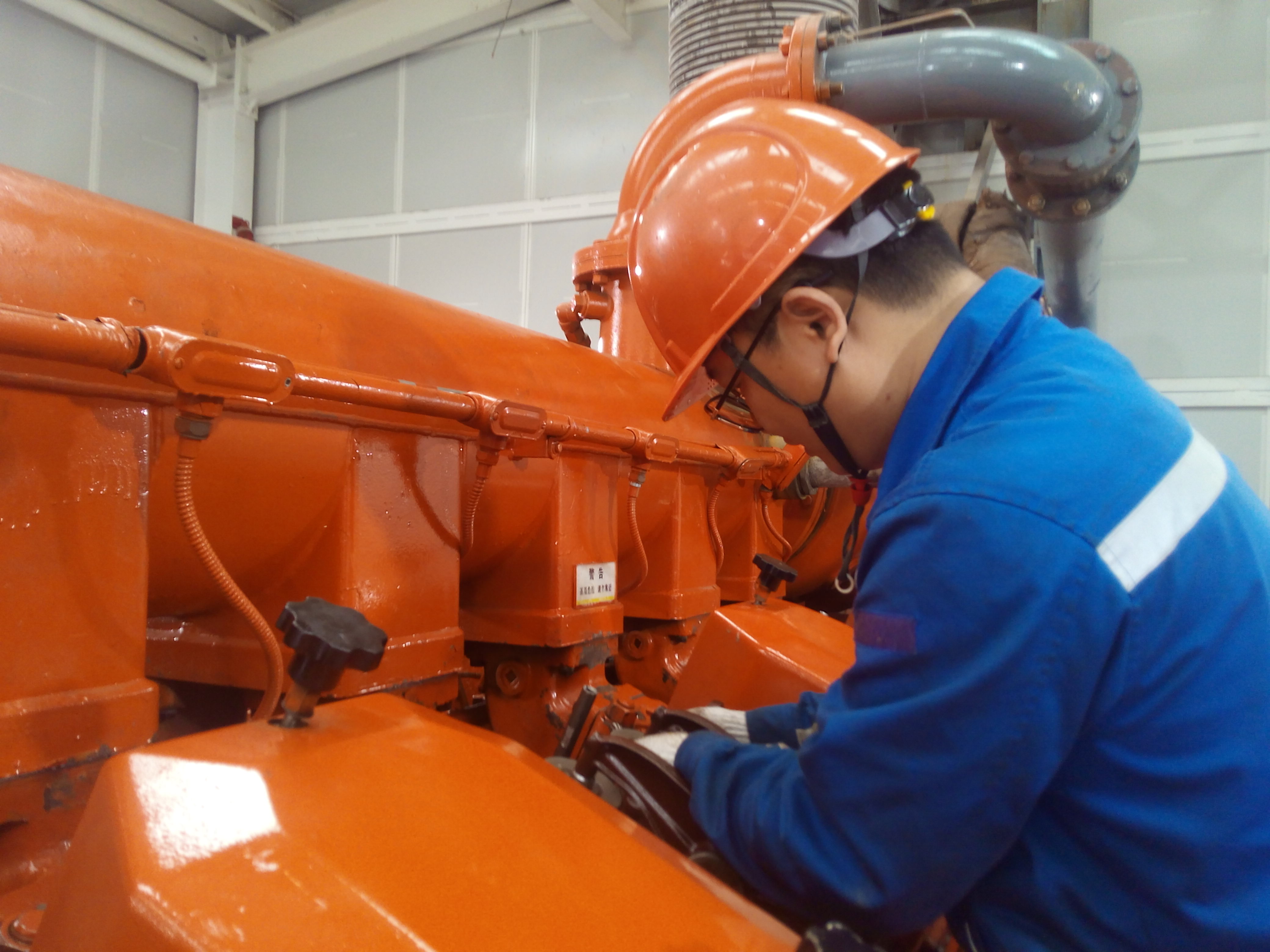 Engineer inspecting orange compressor unit up close